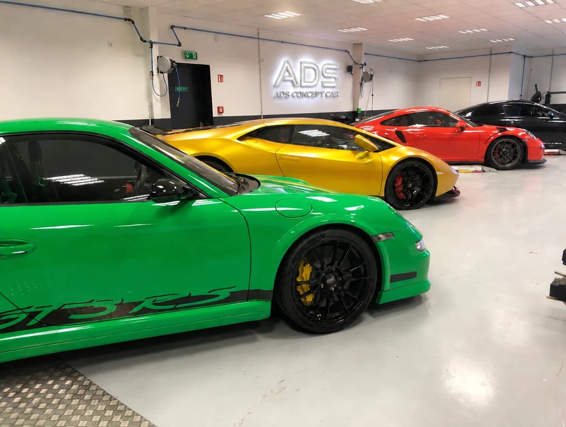 Atelier ADS : 911 GT3 RS verte et Huracán or de profil, GT3 RS rouge en arrière-plan