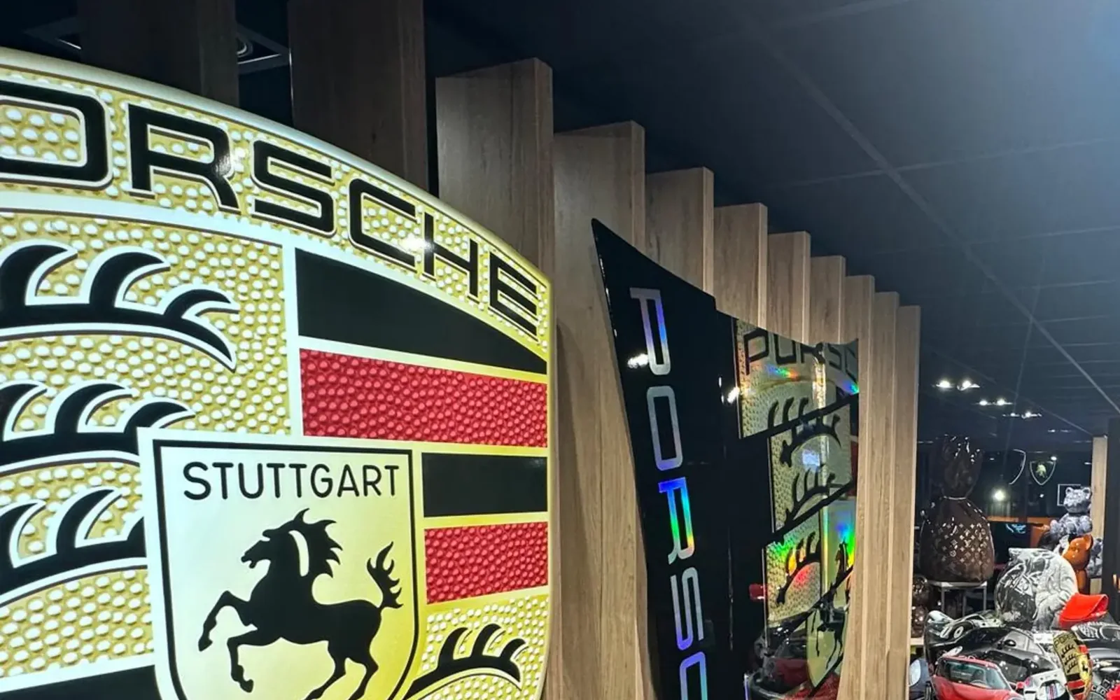 Écusson mural Porsche Stuttgart en relief sur le mur en bois de la boutique