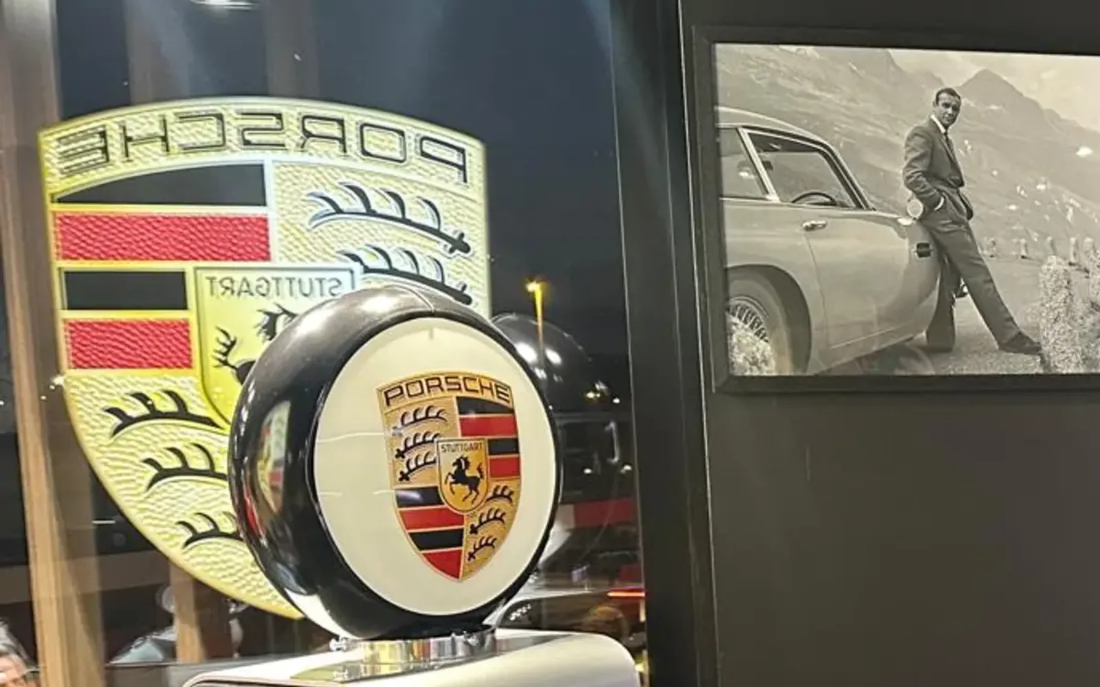 Pompe à essence vintage Porsche numéro 20 devant l’écusson Porsche Stuttgart