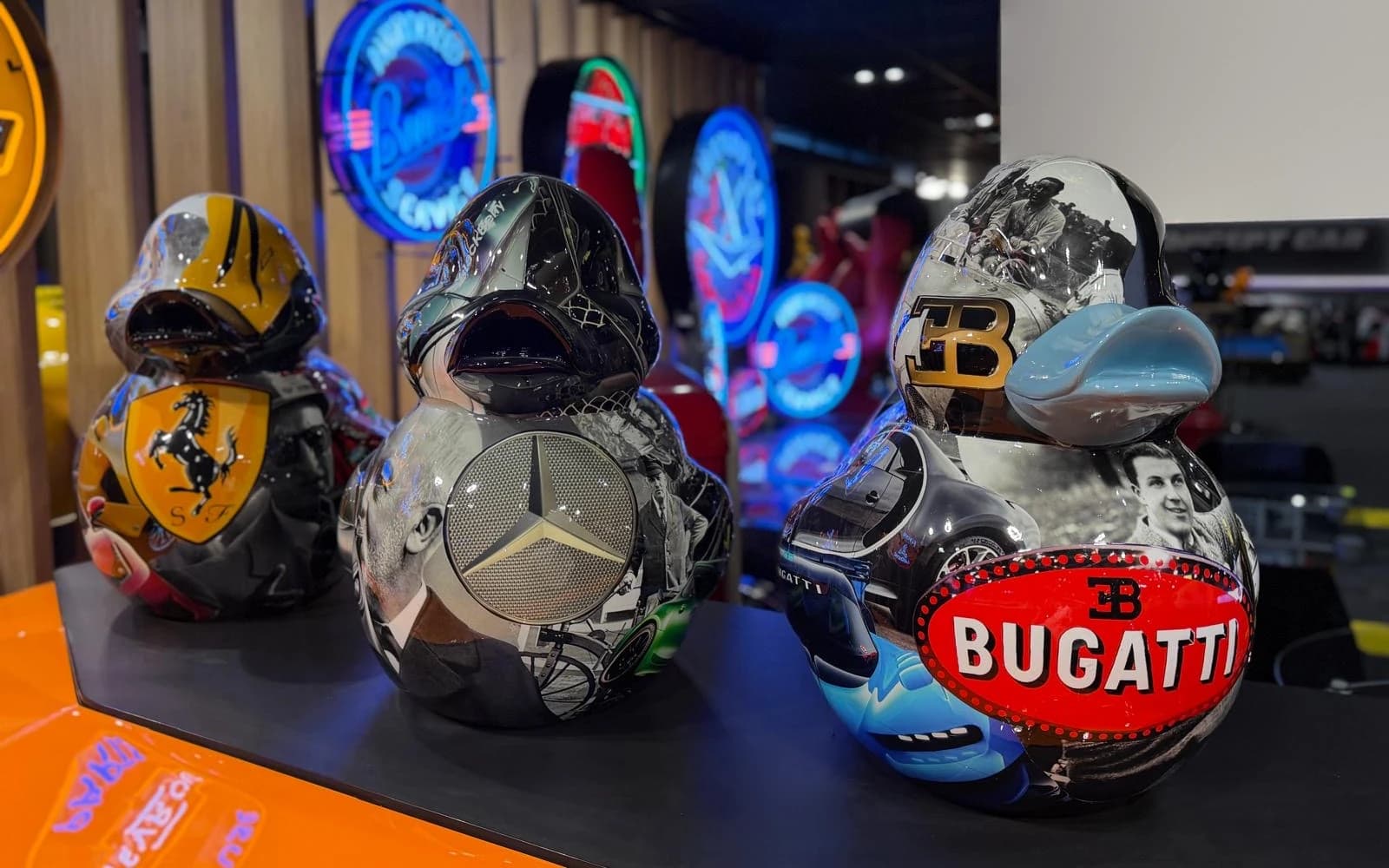 Trois canards pop art Ferrari, Mercedes-Benz et Bugatti devant les néons de la boutique ADS Concept Store