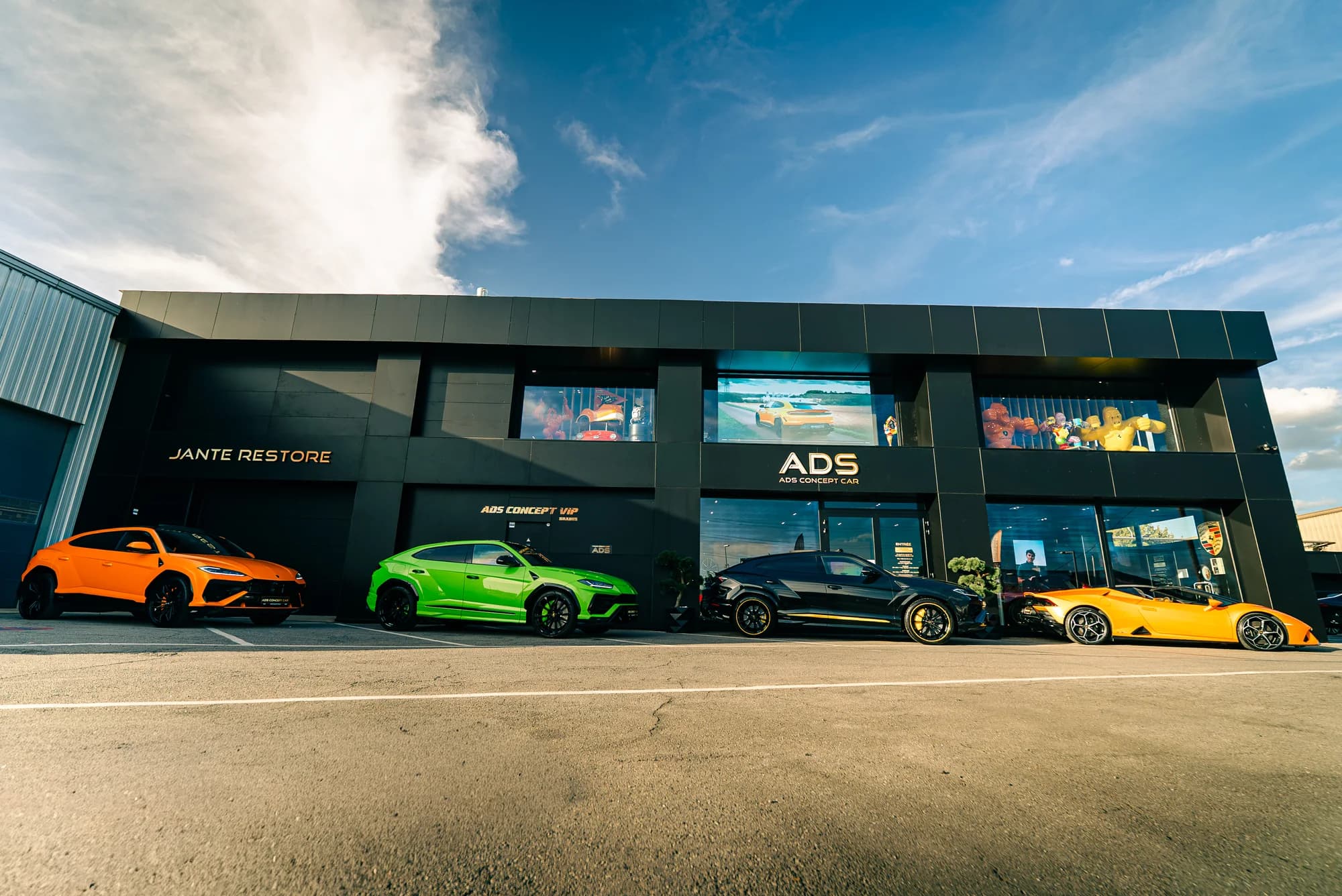 Schriftzug Jante Restore an der schwarzen Fassade des ADS-Showrooms in Foetz, Lamborghini davor aufgereiht