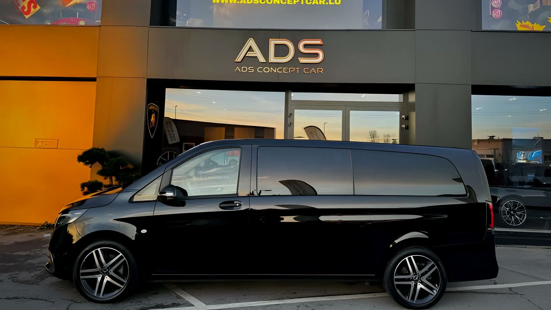 Les quatre intérieurs du Mercedes V VIP — brun, rouge, jaune et bleu — et sa carrosserie noire devant le showroom ADS de Foetz